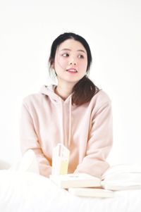 Portrait of a young woman sitting against white wall