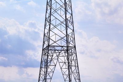 Low angle view of electricity pylon against cloudy sky