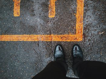 Low section of man standing on wet street