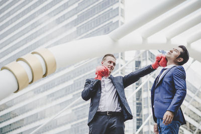 Businessman punching colleague while standing against metallic structure