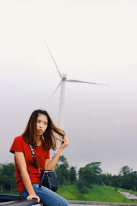 Young woman standing on field against sky