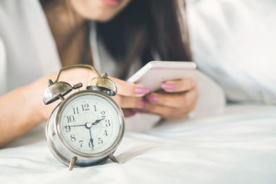 Midsection of woman using mobile phone on bed