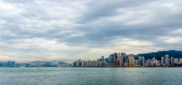 Sea by city buildings against sky