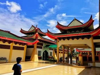Rear view of people outside building against sky