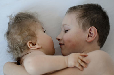 High angle view of siblings on bed