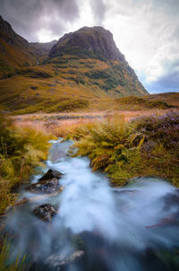 Scenic view of river flowing amidst mountains against sky