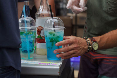 Midsection of man holding blue mojito