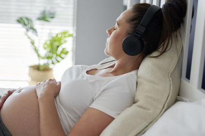 Midsection of woman sitting on window at home