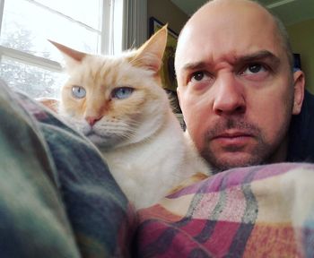 Portrait of man with cat sitting at home