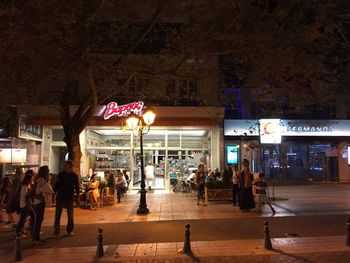 People walking on city street at night