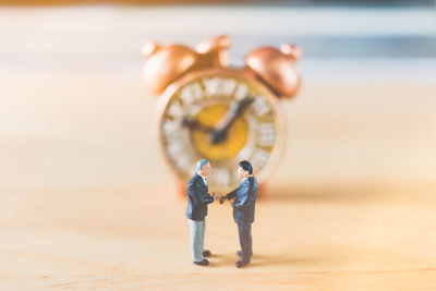 High angle view of figurines with clock on wooden table