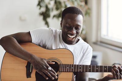 Happy male artist singing while practicing guitar in classroom