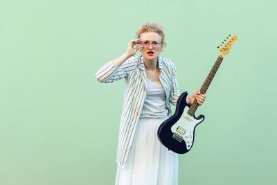 Young man playing guitar against gray background