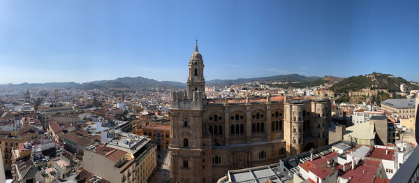 Aerial view of buildings in city against blue sky