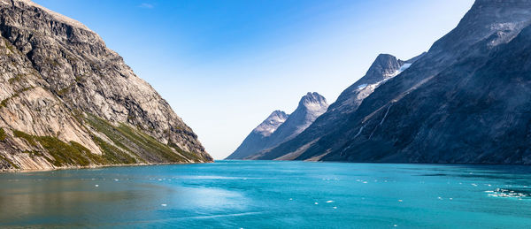 Scenic view of lake and mountains against blue sky