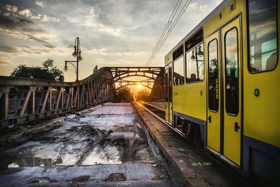 Train on bridge against sky during sunset