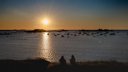Silhouette people on beach against sky during sunset