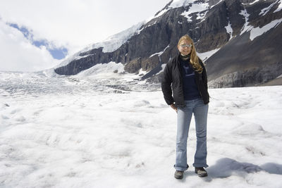 Young woman standing against snowcapped mountain