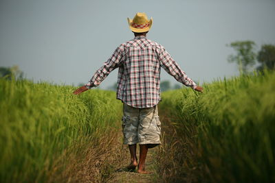 Rear view of woman standing in farm against sky