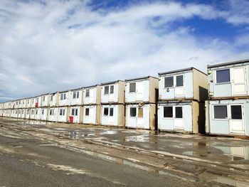 Empty road by abandoned building against sky