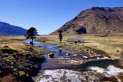 Scenic view of landscape and mountains against clear blue sky