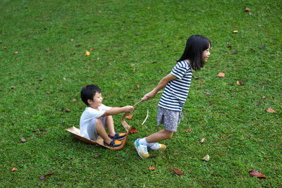 High angle view of siblings playing on grassy field at park