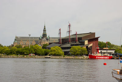 Buildings by river against sky in city