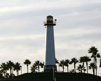 Low angle view of palm trees and lighthouse against sky