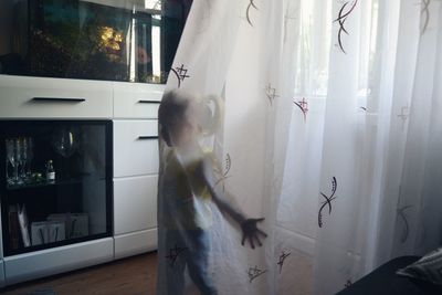 Blurred motion of woman standing by window at home