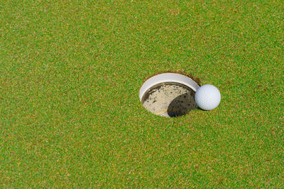 Golf ball on lip of cup at golf court.