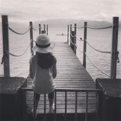 Girl sitting on railing against sea