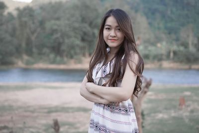 Woman in dress standing by river against mountain