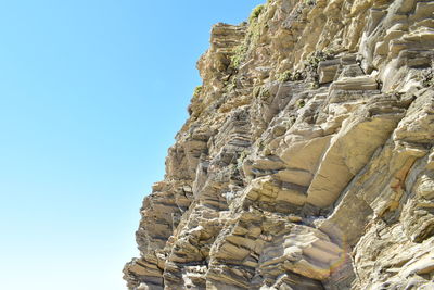 Low angle view of rocky mountain against clear sky