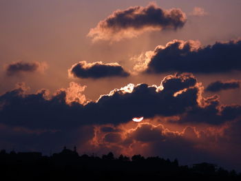 Low angle view of silhouette trees against dramatic sky