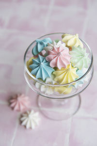 Small colorful meringues in the glass on pink tile background