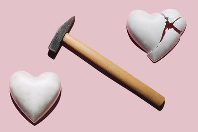 Concrete heart, hammer and broken plaster heart on pastel pink background. minimalist concept. 