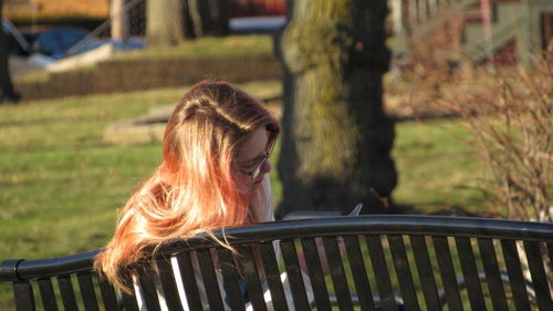 Woman using mobile phone while sitting on bench