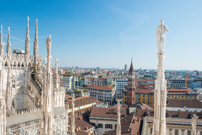 View to spires and statues on roof of duomo through ornate marble fencing. milan, italy