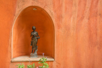 Statue against orange wall of building