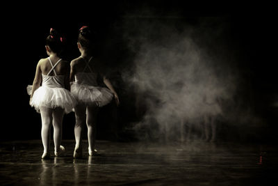 Rear view of ballet dancers walking on stage