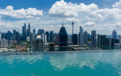 Modern buildings by swimming pool in city against sky