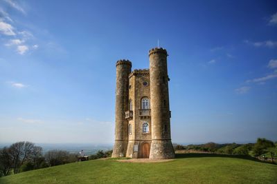 Old ruin tower on field against blue sky