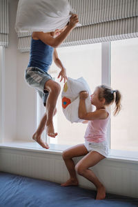 Brother and sister playing at home pillow fight