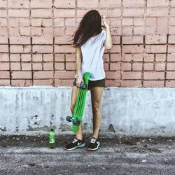 Young woman leaning on brick wall