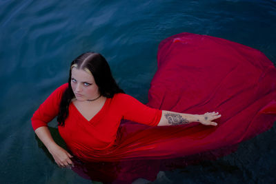 Portrait of young woman sitting by lake