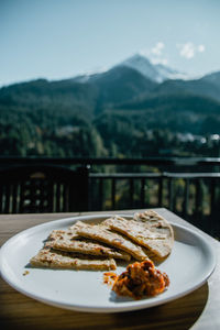 Close-up of food in plate on table against mountains