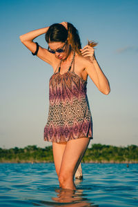 Midsection of young woman standing against sea