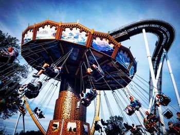 Low angle view of chain swing ride against sky