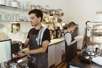 Male barista preparing coffee using coffee maker in cafe