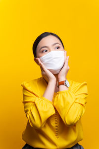 Portrait of a beautiful young woman against yellow background